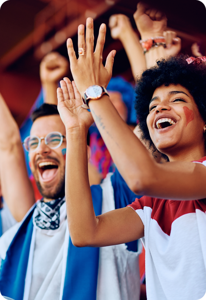 Two people standing and applauding at a soccer game.